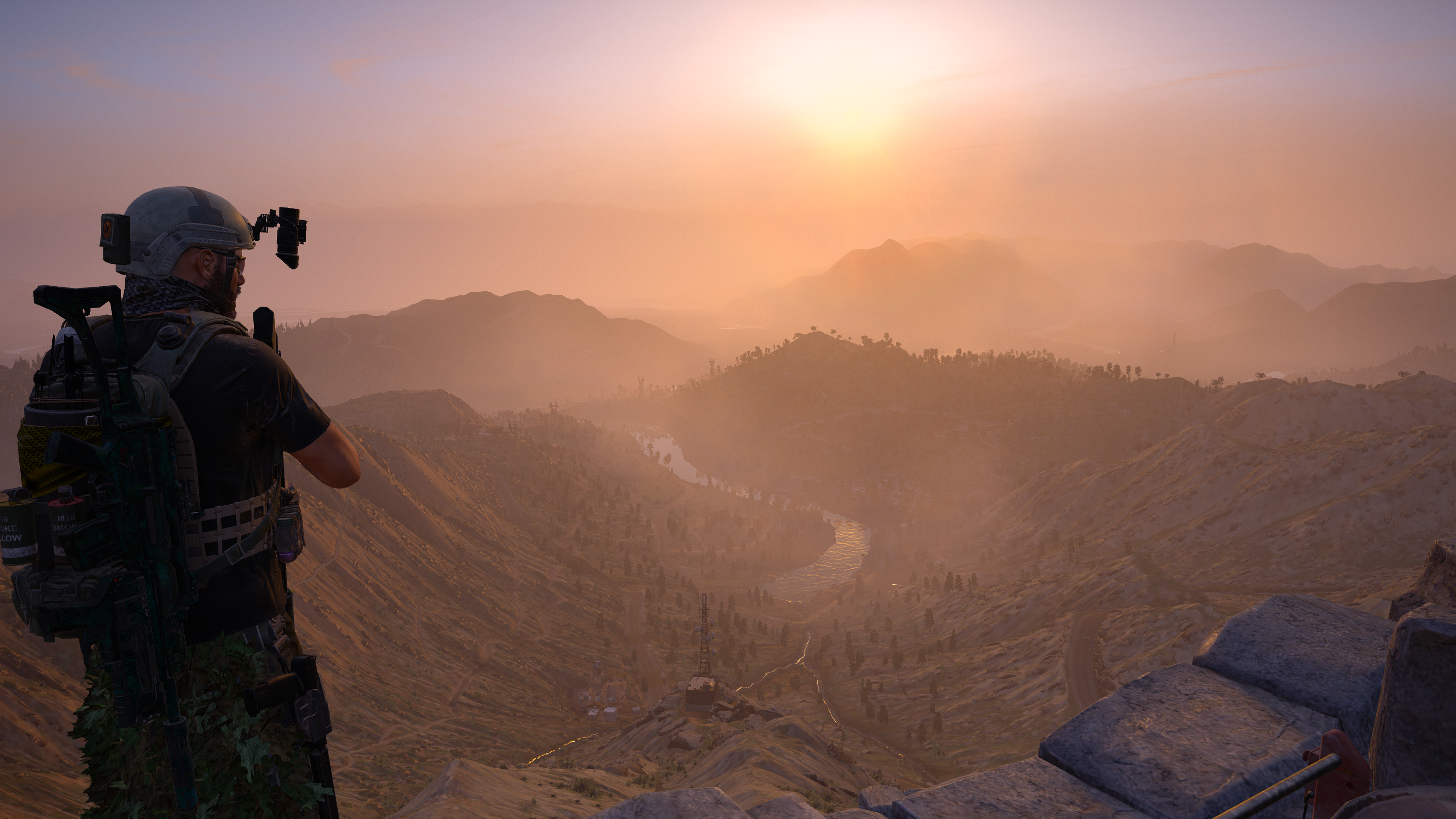 Screenshot from Ghost Recon Wildlands showing a soldier looking out over the stunning Bolivian landscape during a hazy sunrise.